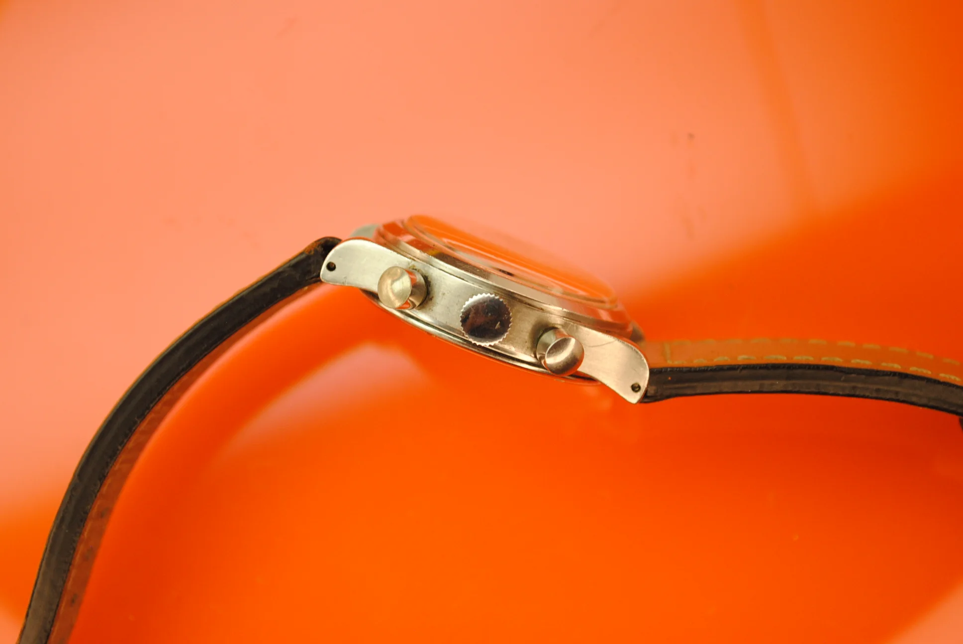 Profile view of the sold Unver chronograph showing its crown, twin pushers, case, and domed crystal