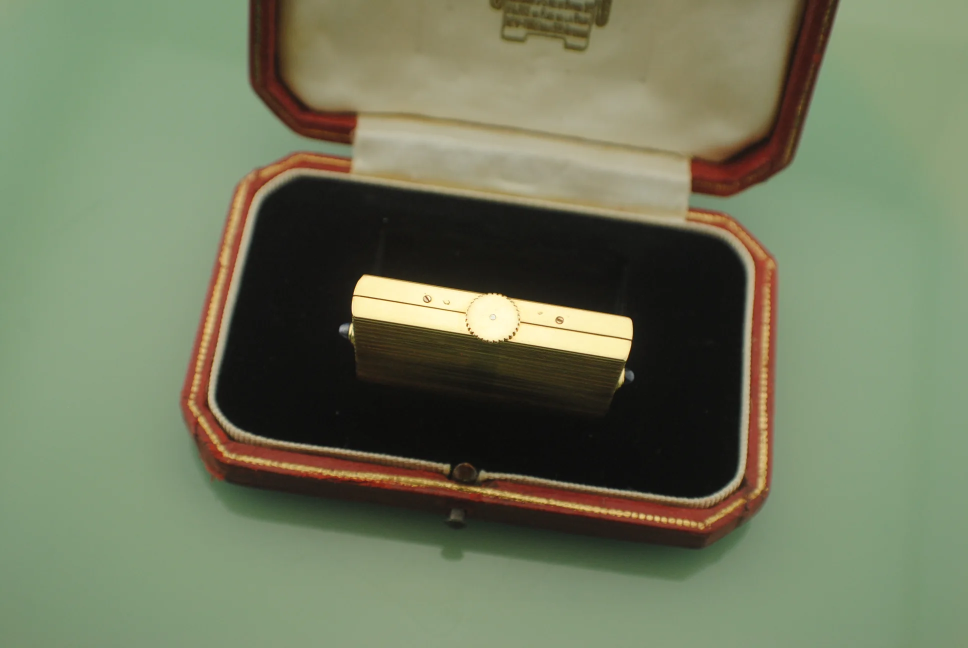 Side view of the closed yellow-gold Cartier Guillotine watch showing the central circular crown detail