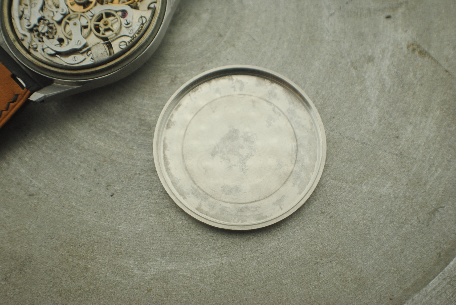 Interior of the removed screw-down caseback beside the open Marvin chronograph